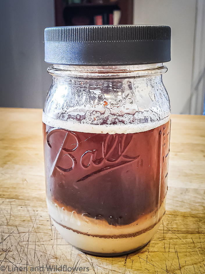 Freshly pored hot bacon grease in a Ball mason jar with a grey lid ready for long term storage.