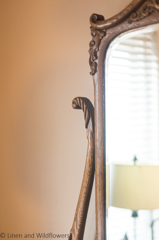 The details of a mirror on the Victorian dresser with scalloped & floral carved wood.