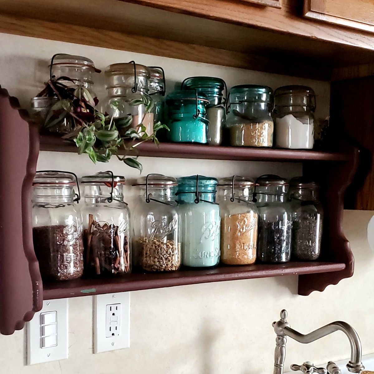 A wooden shelf with jars of various sizes and colors, filled with spices and ingredients. A small plant adds greenery. The scene is cozy and rustic.