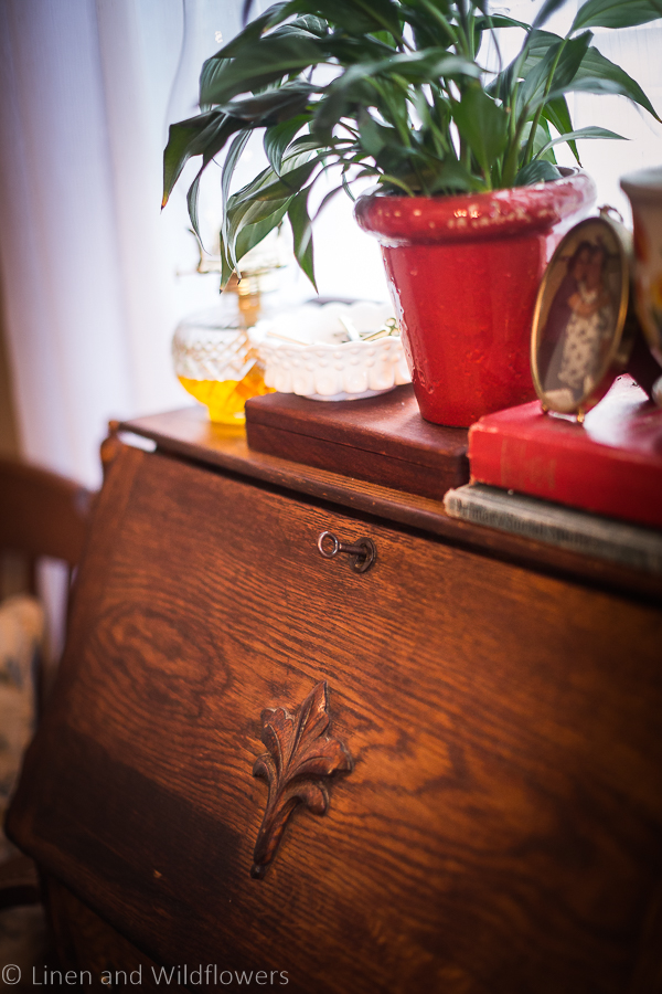 Plants & decor items on top of a secretary desk, focused on key in lock of desk.
