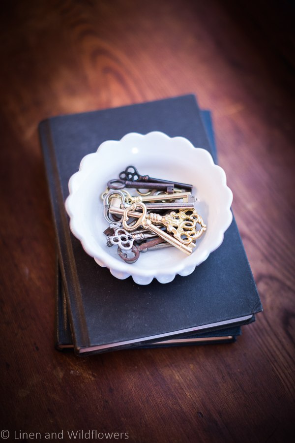 replica skeleton keys in a milk glass dish sitting on old books
