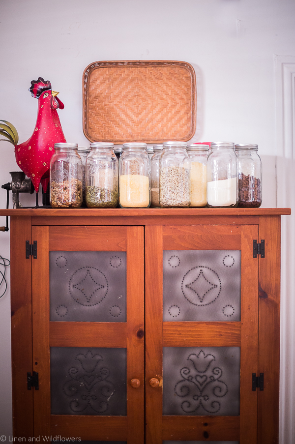 Mason jars filled with dried good on top of Pie cabinet