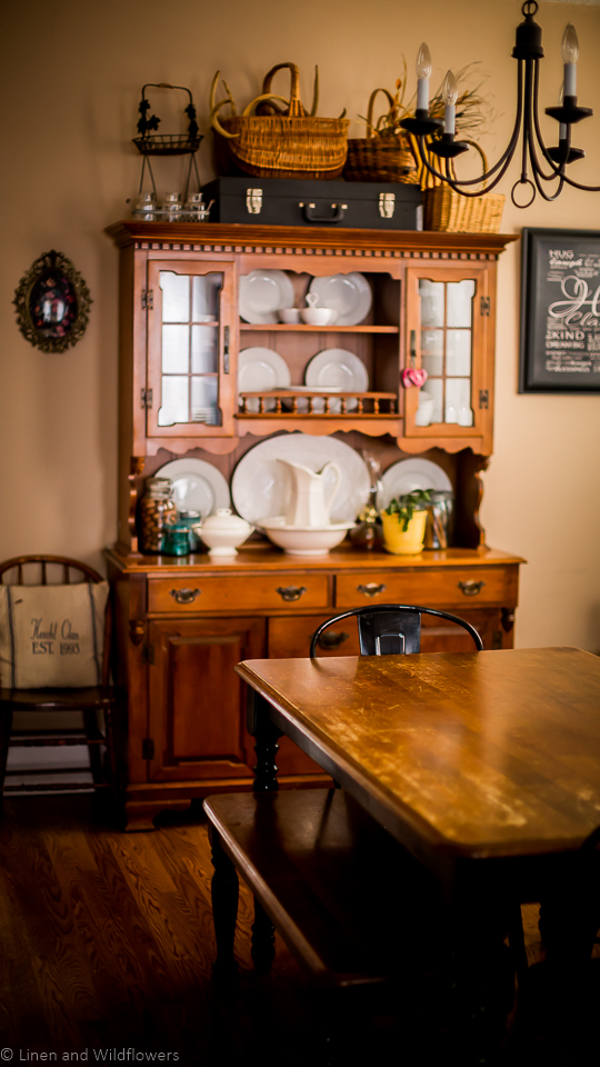 a dining room with a hutch filled with china & a dining room table & black metal chairs.