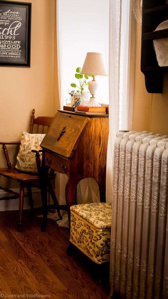 antique secretary desk, floral knitting box, a chair with a pillow & a radiator