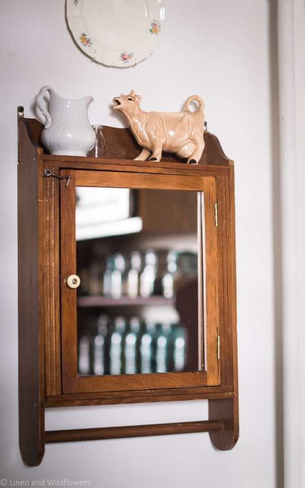 Antique Medicine cabinet with a small white porcelain pitcher and a brown ceremaic cow.