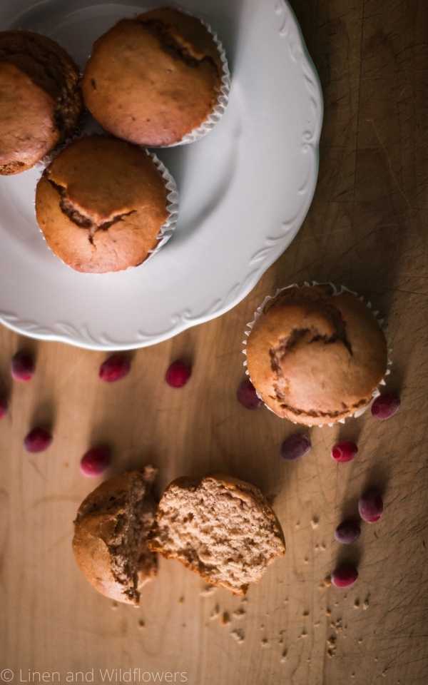 Cranberry sauce muffins is one of the 5 easy & quick snack recipes that is included for a healthy snack. A plate with cranberry sauce muffins that is surrounded by fresh cranberries, a muffin & a broken in half muffin.