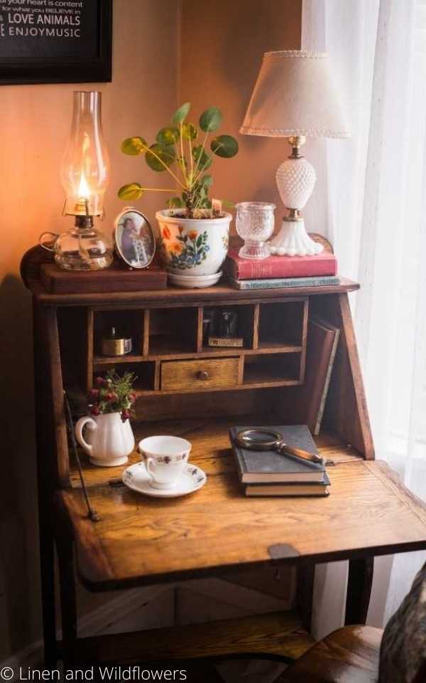 5 Decor Inspirations Posts-A secretary desk with alit oil lam[p and filled with antique decor & a plant,.