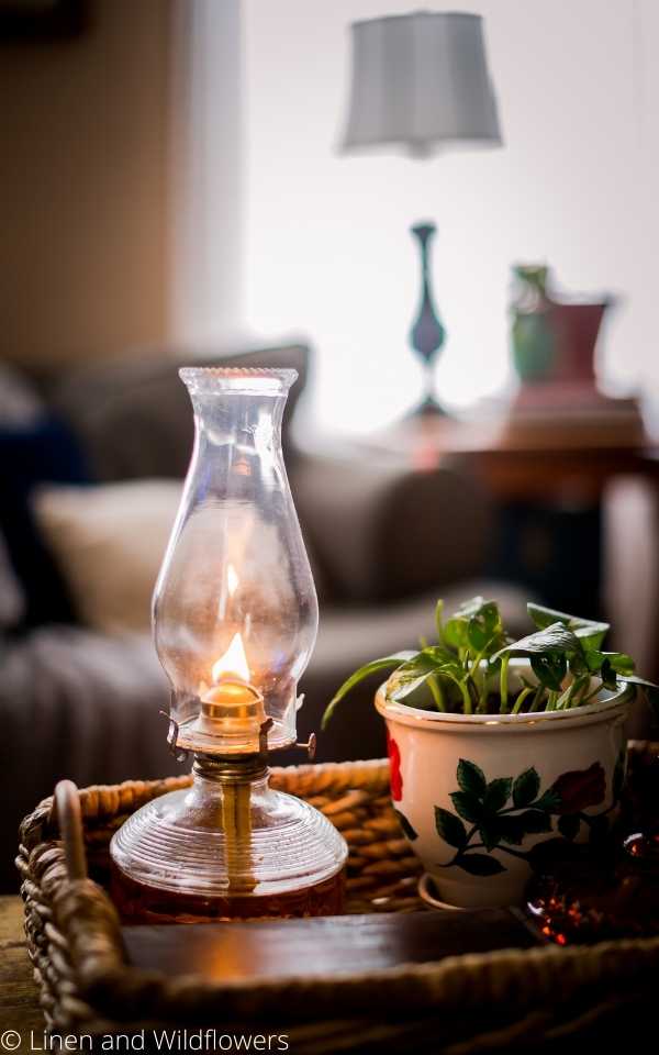 a basket that holds a lit oil lamp, small box & a plant.