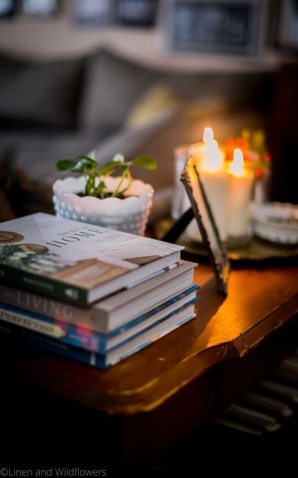 I am sharing 10 Stylish Ways for Using Books for Decorating in the home that will give you a different approach to adding a timeless feel to your space. A stack of books on a console table with a plant, photo frame & a tray with candles, milk glass bowl & vase with flowers.