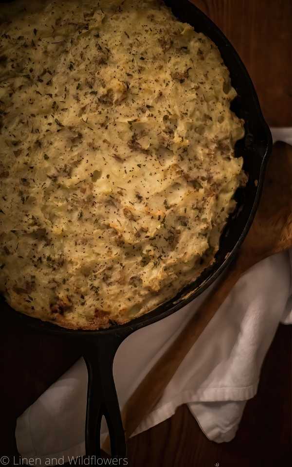 Shephard's Pie with ground turkey mixed with chicken broth, garlic, black pepper, and onions topped with fluffy mashed potatoes baked in the oven to deliciousness. Serve with a side of vegetables in a cast iron skillet.