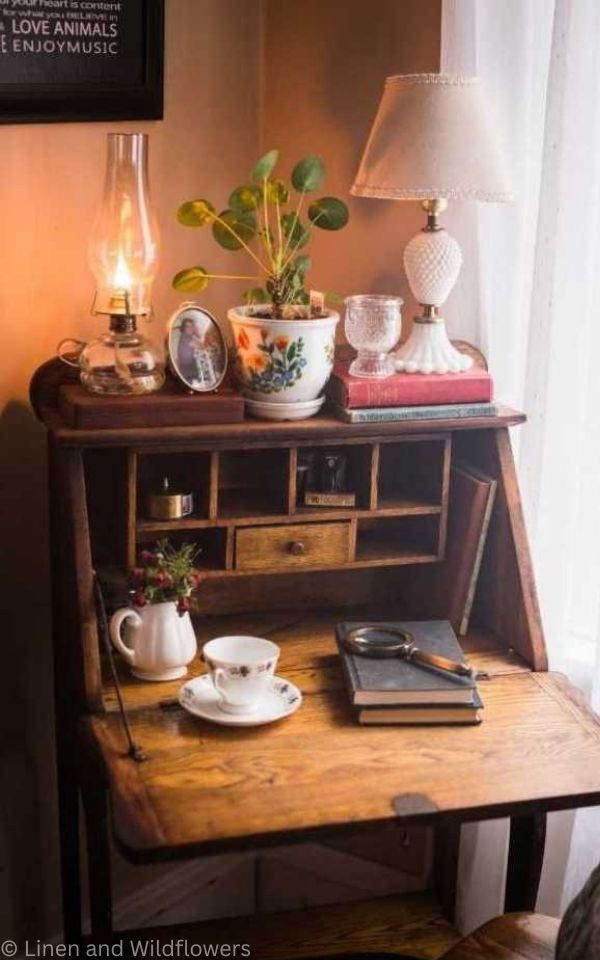 A secretary desk with an assorted of vintage & antique items thats sits on it.
