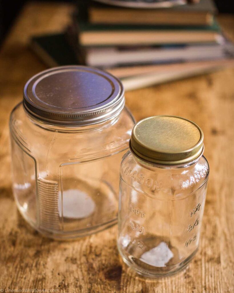 2 glass jars in front of a tack of old books.