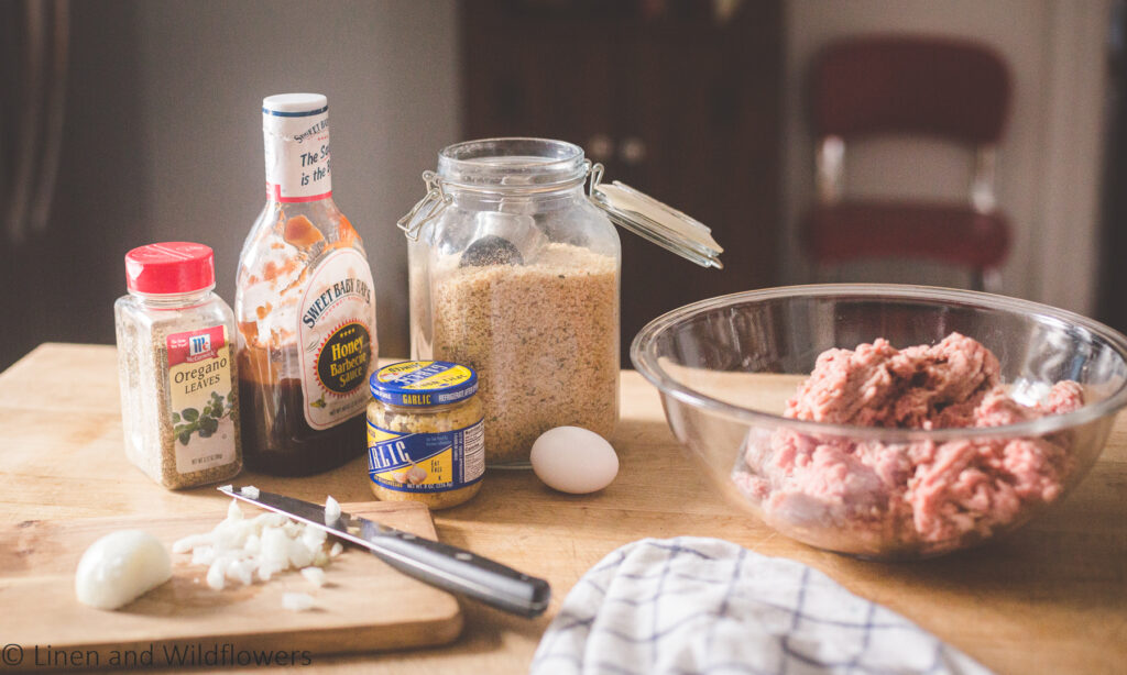 Ingredients to make turkey meatloaf. Sweet Baby Rays BBQ Sauce, Oregano, minced garlic, an egg, onions, Italian style breadcrumbs to make turkey meatloaf.