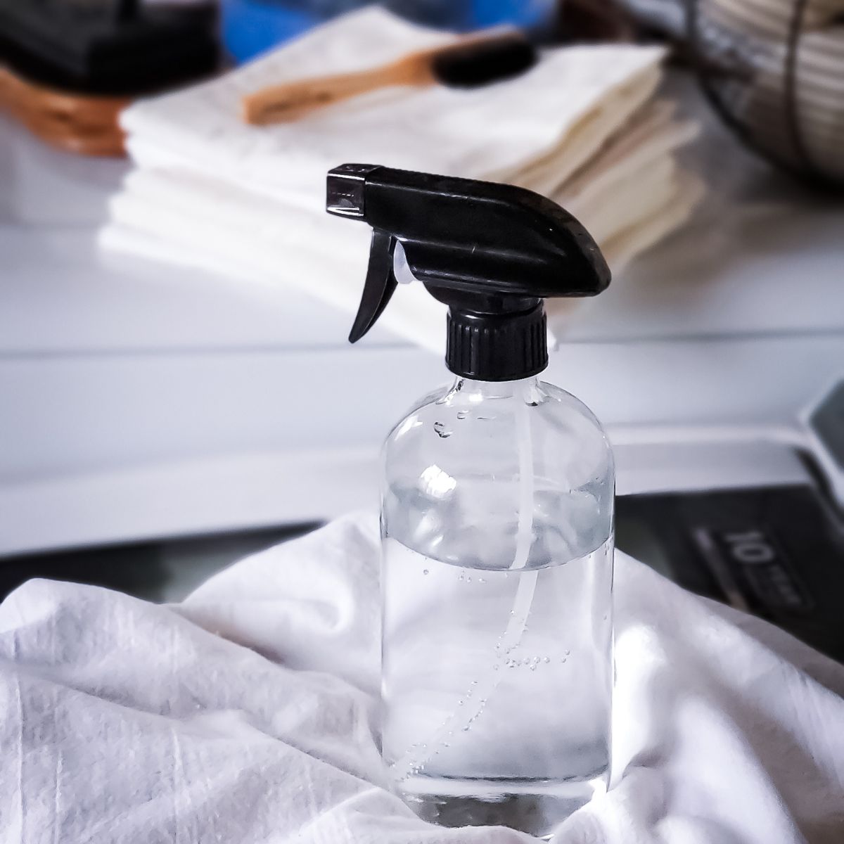 How to Make Natural Laundry Stain Remover-Spray bottle with a homemade stain remover sitting on top of a linen towel.