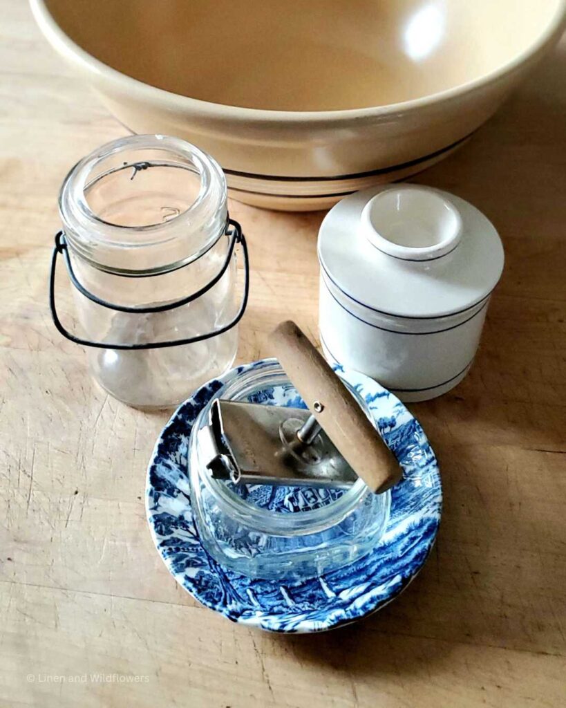Vintage Kitchen tools: A blue & white plate, can opener, two mason jars, butter crock & a large mixing bowl.