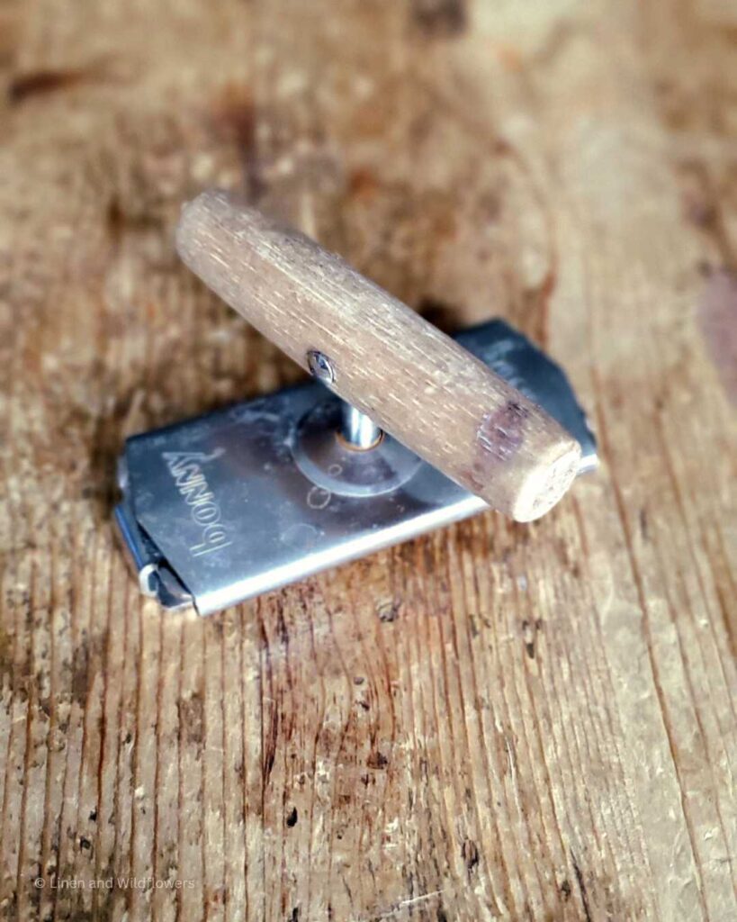 A vintage can opener with a wooden handle