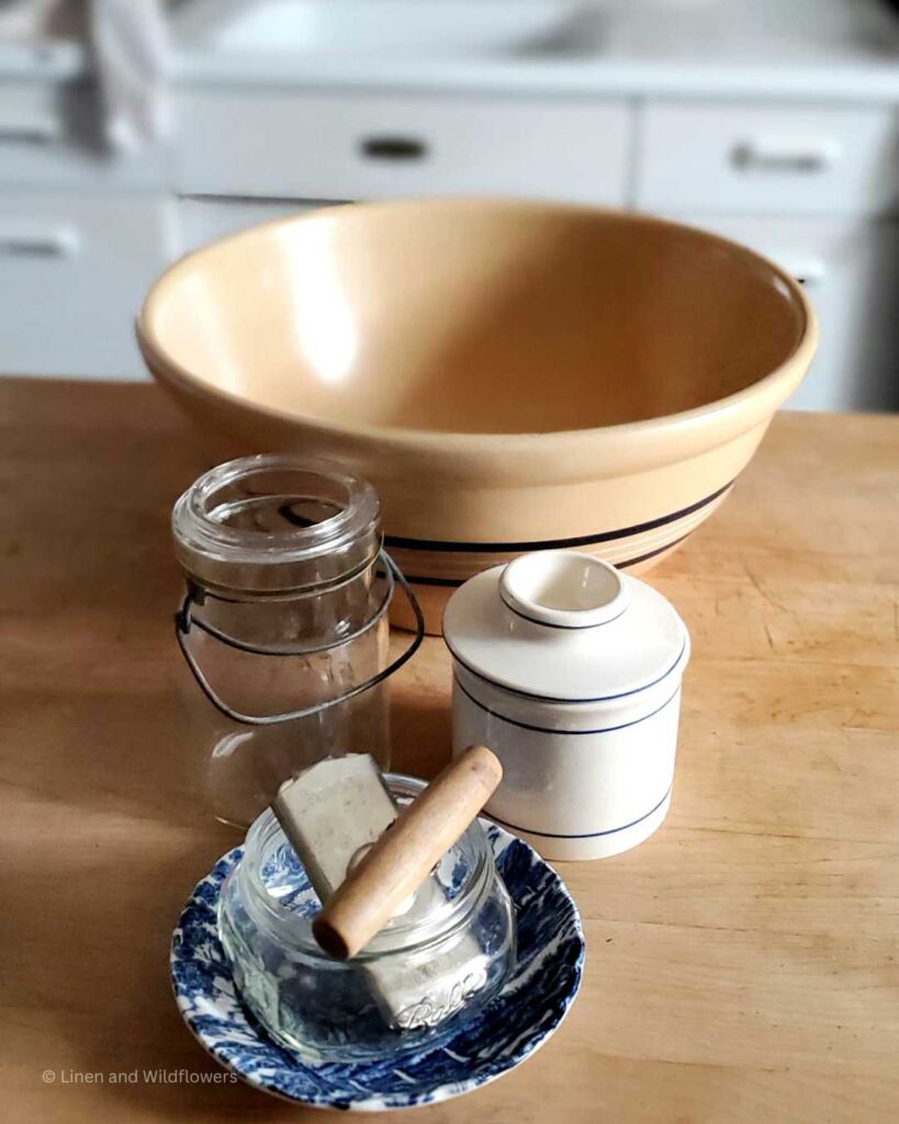 Vintage Kitchen tools: A blue & white plate, can opener, two mason jars, butter crock & a large mixing bowl.