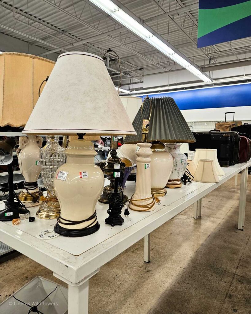 A table filled with a variety of lamps for sale in a Goodwill Thrift Store.