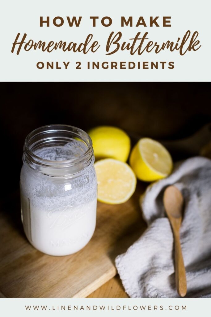 Homemade buttermilk in a mason jar only using 2 ingredients. Next to the jar is a cut lemon nxt to another lemon, a wooden spoon on a white towel next to a cutting board.