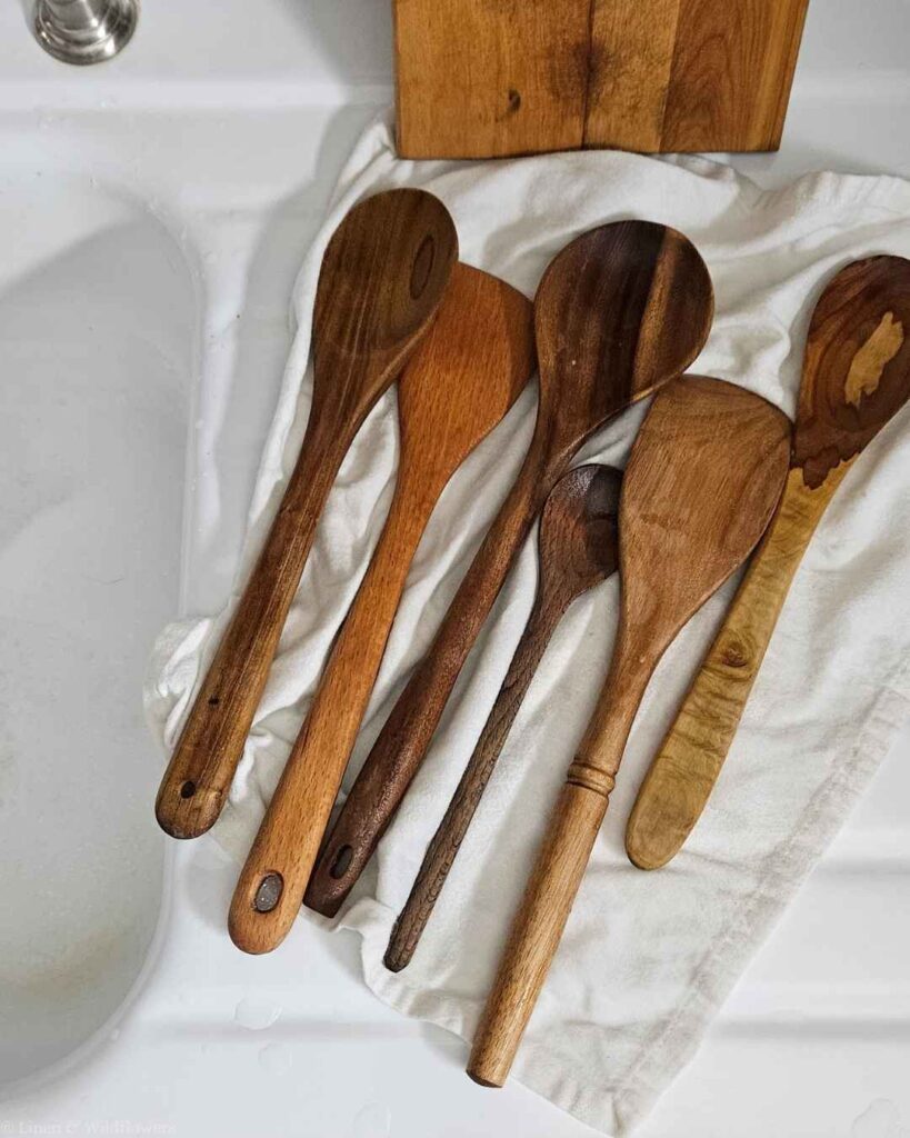 Assorted wooden spoons air-drying on a linen towel after being washed and sanitized.