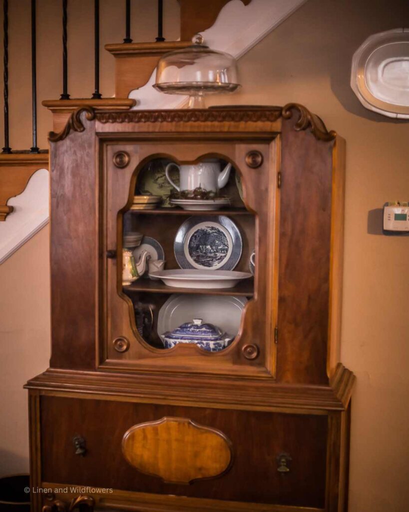 An antique China hutch filled with a variety of dishes on display making a statement piece in a space.