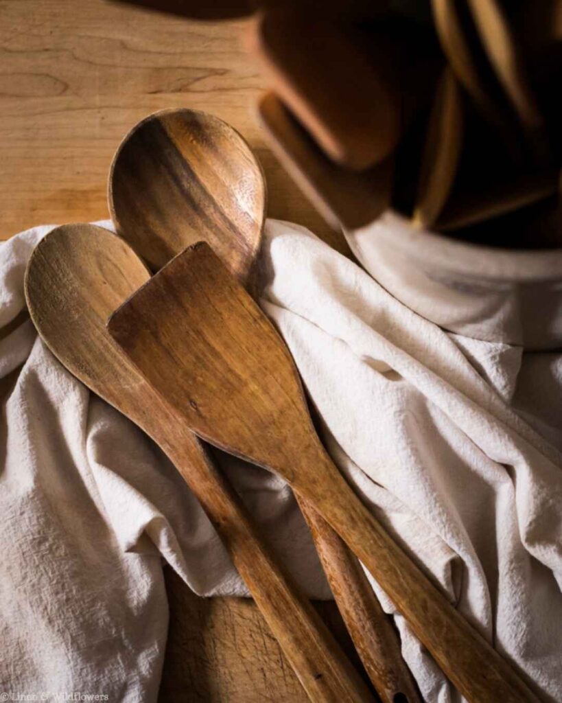 Wooden spoons and spatula resting on a linen cloth, showing proper care and storage for wooden kitchen utensils.