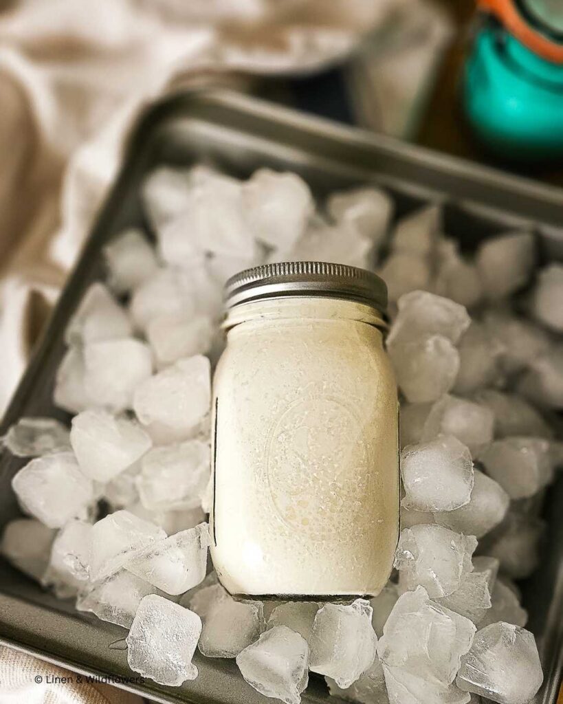 A jar of homemade ice cream laying on a pan of ice to freeze quickly for enjoyment.