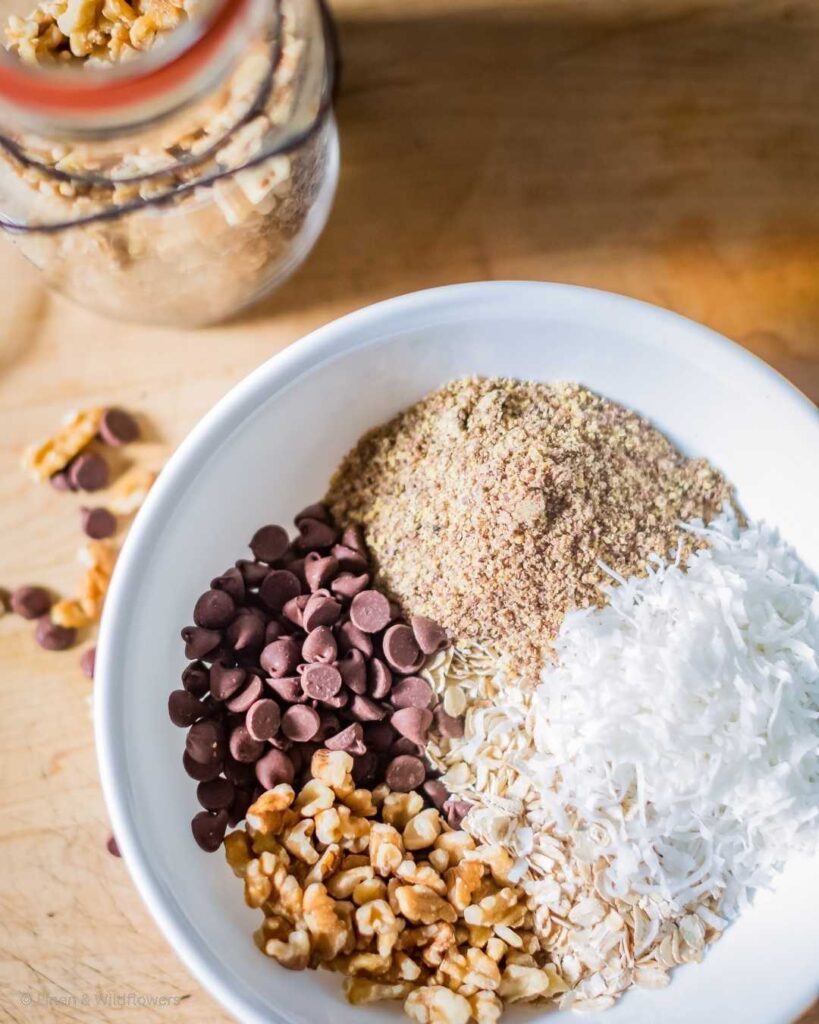 A bowl of ingredients such as coconut, chocolate chip morsels, brown sugar & oats for making homemade granola.