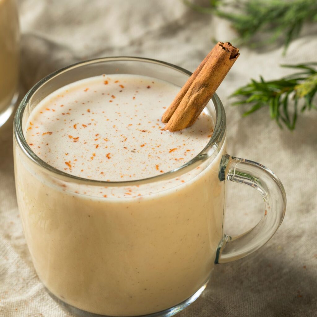 A glass mug of homemade non-alcoholic eggnog with a cinnamon stick.