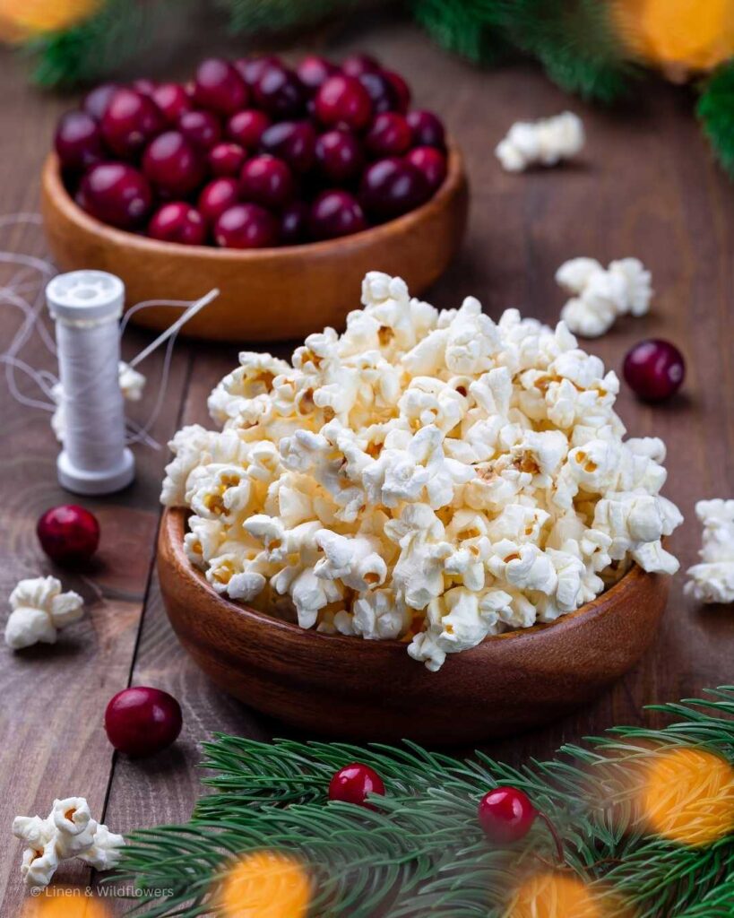 two wood bowls each filled with cranberries & popcorn to make a homemade Christmas tree garland.