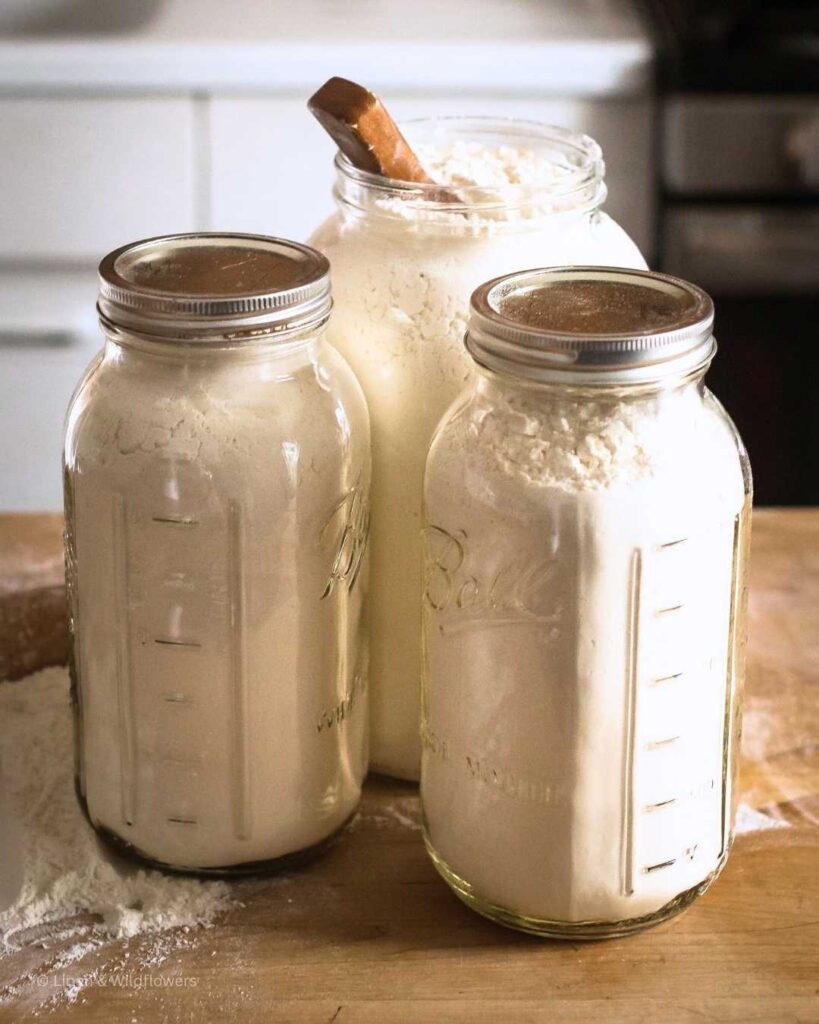 A gallon & two 64oz Ball Mason Jars filled with flour for long-tern storage.