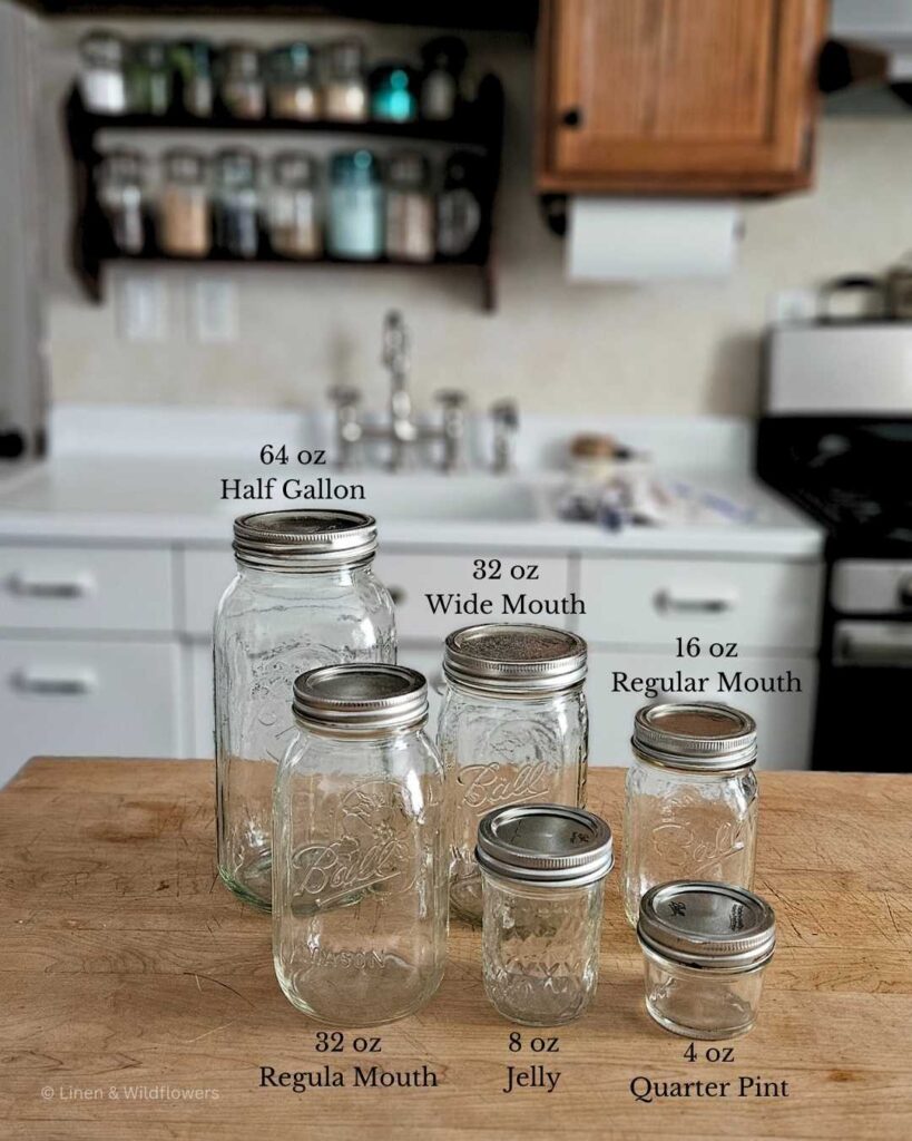 Various of sizes of Ball Mason Jars labeled with size on a butcher block in front of a vintage kitchen sink.