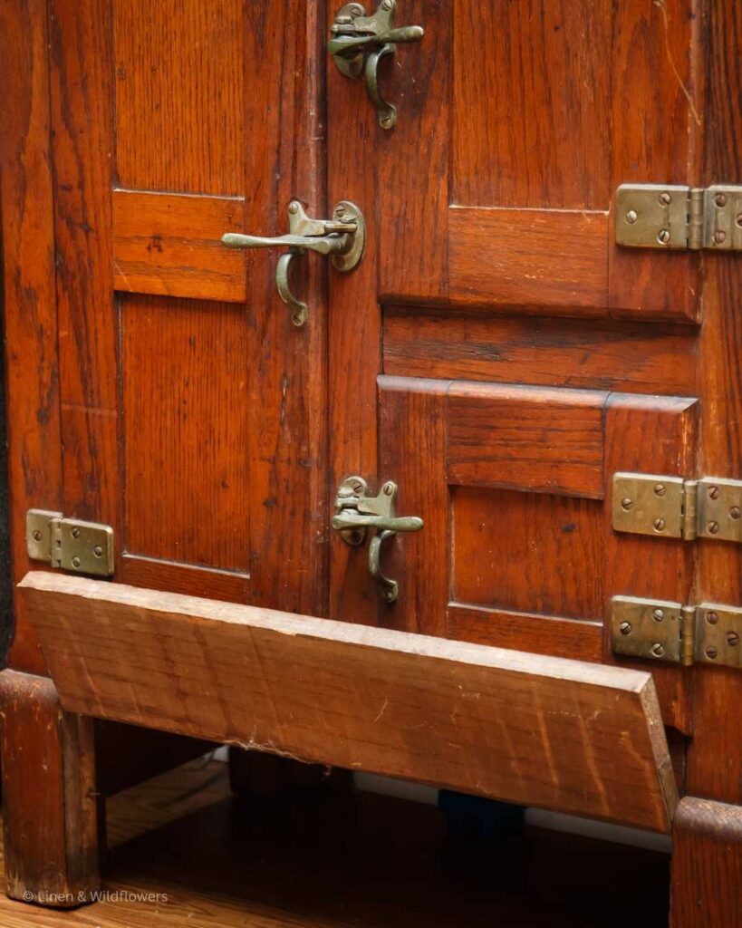 A Victorian icebox original hardware with beautiful patina. The bottom of the icebox, shows a front panel that lifts up for a tray to collect water from melting ice.