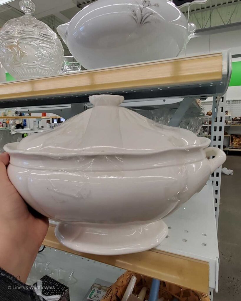 A ironstone gravy boat with ladle for sale in a thrift store.