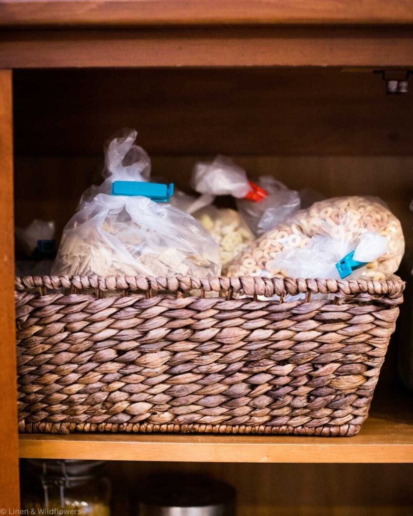 Three mason jars filled with white flour sit on a wooden table. Two have lids, and the third is open with a wooden scoop inside.