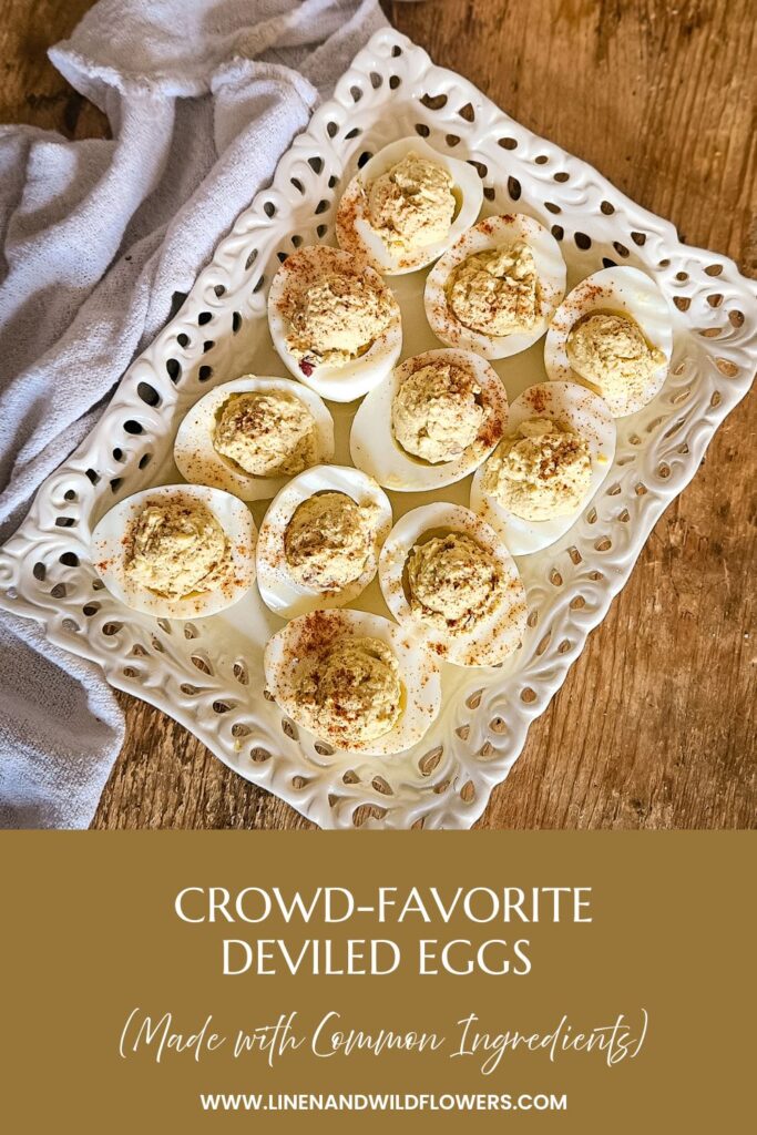 A white platter of deviled eggs sprinkled with paprika on a rustic wooden table. A soft, gray cloth lies beside them. Text reads "Crowd-Favorite Deviled Eggs."