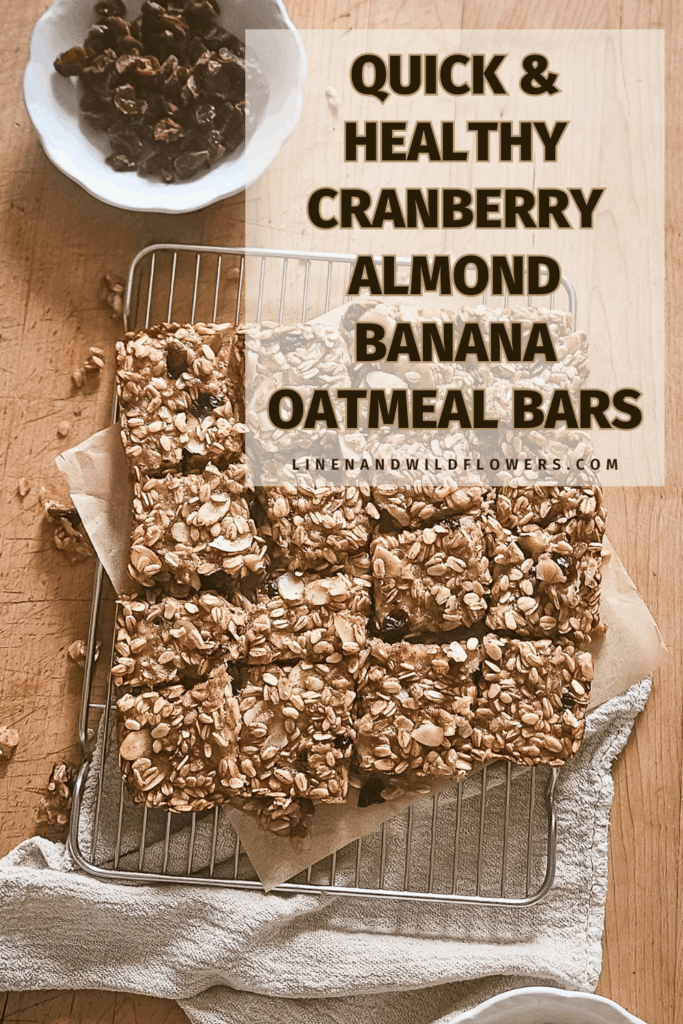 Tray of oatmeal bars with visible oats and almonds rests on parchment paper atop a wire rack. Text reads "Quick & Healthy Cranberry Almond Banana Oatmeal Bars." A bowl of cranberries is nearby. Warm, rustic tone.