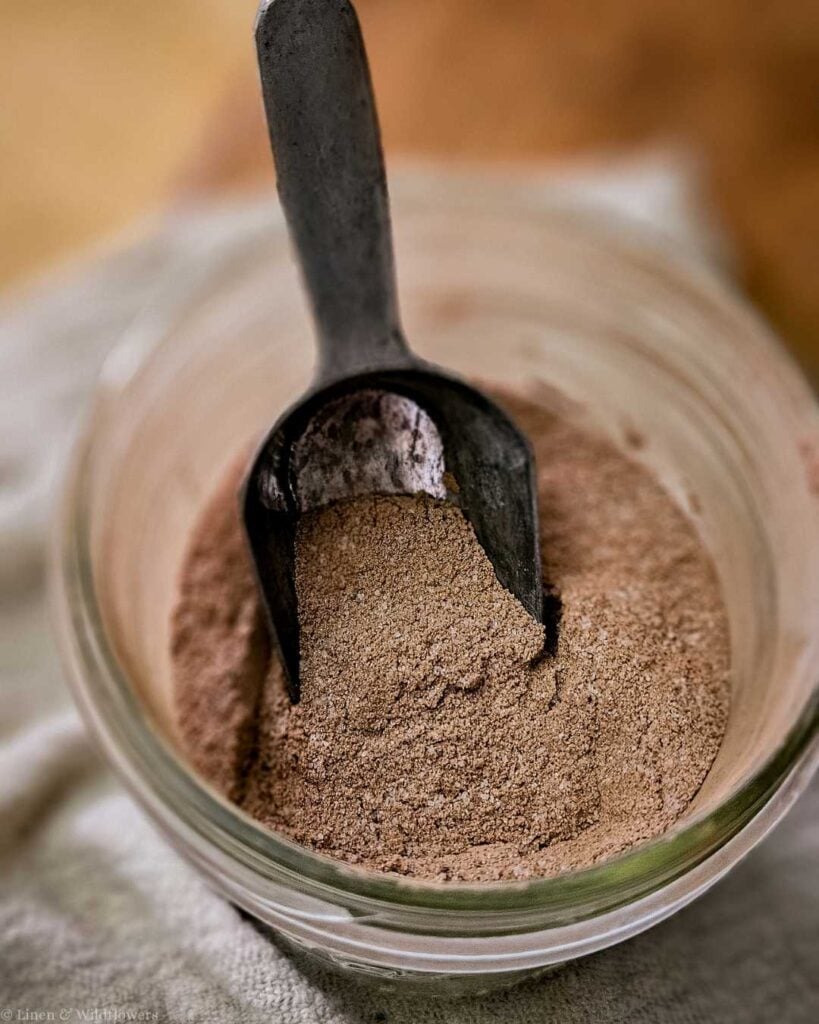 Homemade brownie mix stored in a mason jar with a metal scoop.