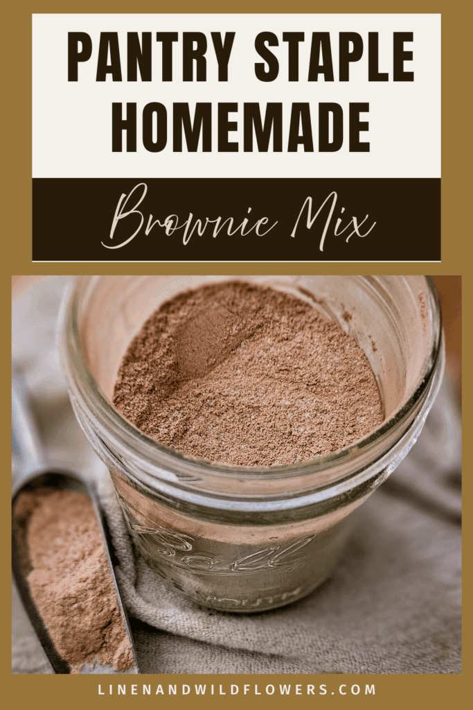 "Brownie mix in a glass jar on a linen cloth with a metal scoop of cocoa powder. Text reads 'Pantry Staple Homemade Brownie Mix.'"
