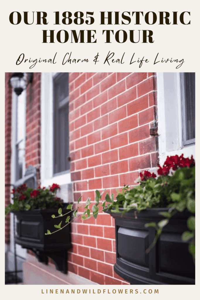 Brick exterior of a historic 1885 home with black window boxes filled with vibrant red flowers. Text reads 'Our 1885 Historic Home Tour: Original Charm & Real Life Living'.