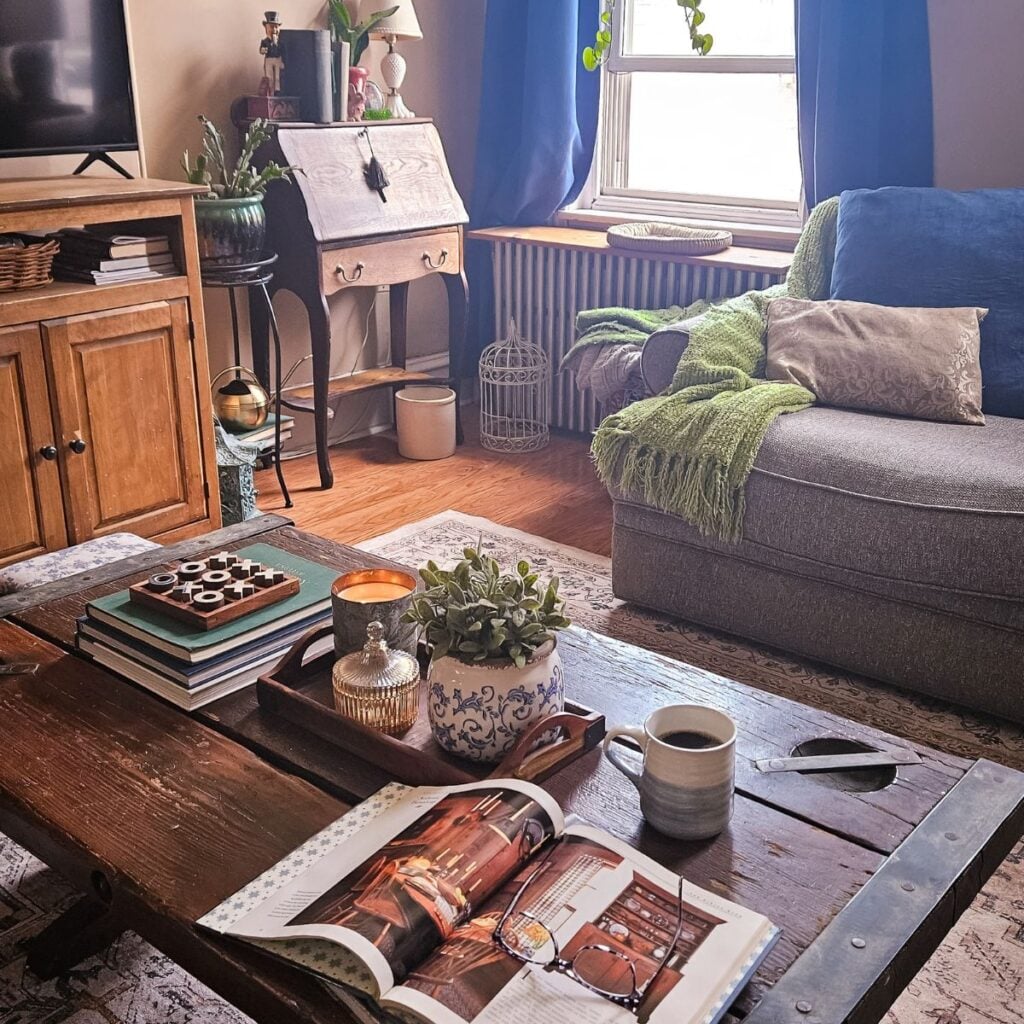 Cozy home decor with thrifted finds in a warm living room featuring layered textiles, wooden furniture, and soft natural light.