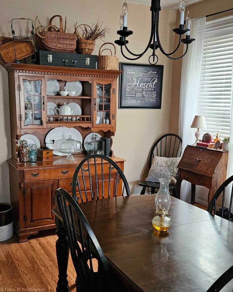Collected home decor on a budget featuring antique hutch with ironstone dishes and Windsor chairs.