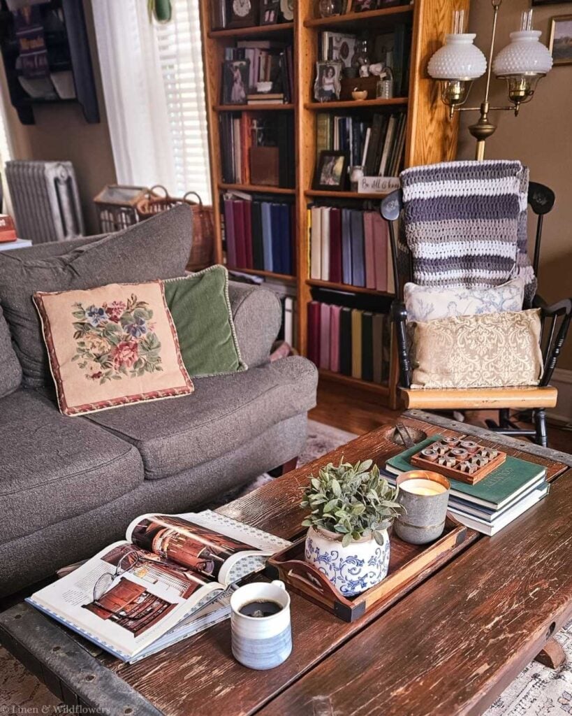 Thrifted coffee table styled with vintage books, candle, and plant for a collected home aesthetic on a budget.