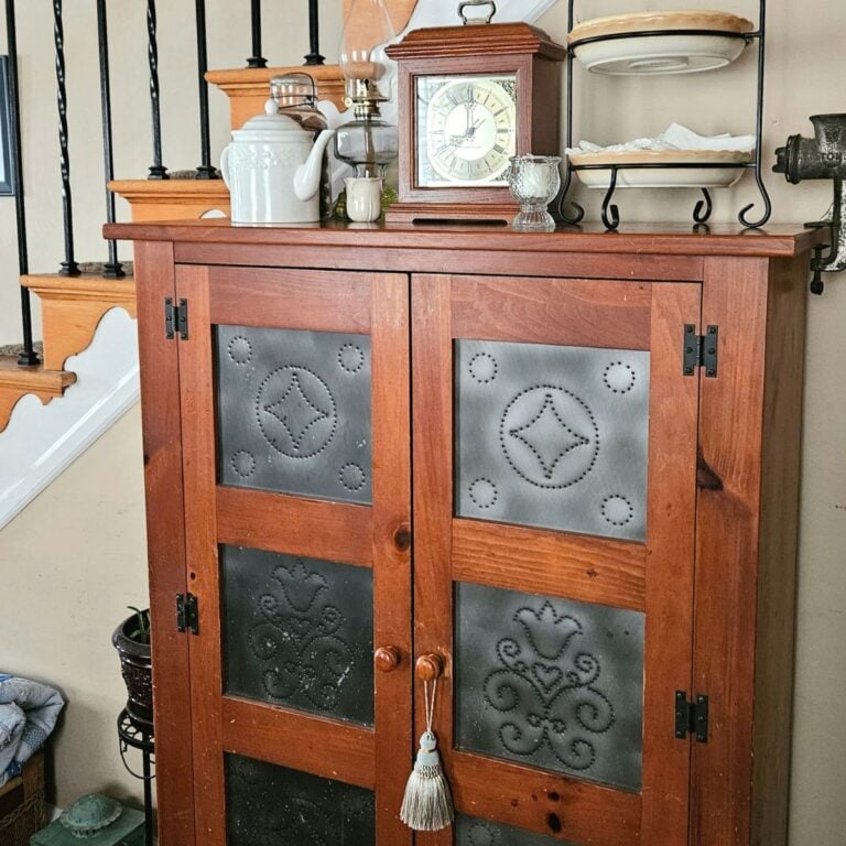 How to create a collected home on a budget with a vintage punched tin pie safe styled with a mantel clock and oil lamp.