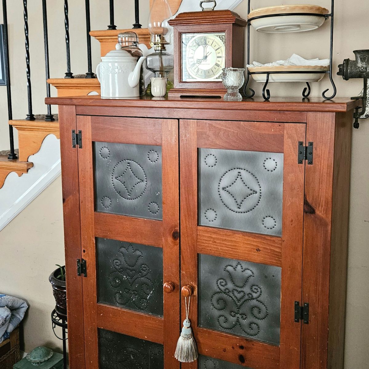 How to create a collected home on a budget with a vintage punched tin pie safe styled with a mantel clock and oil lamp.