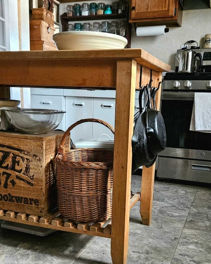 Vintage storage idea using an antique wood crate and wicker basket for extra storage under a kitchen island.