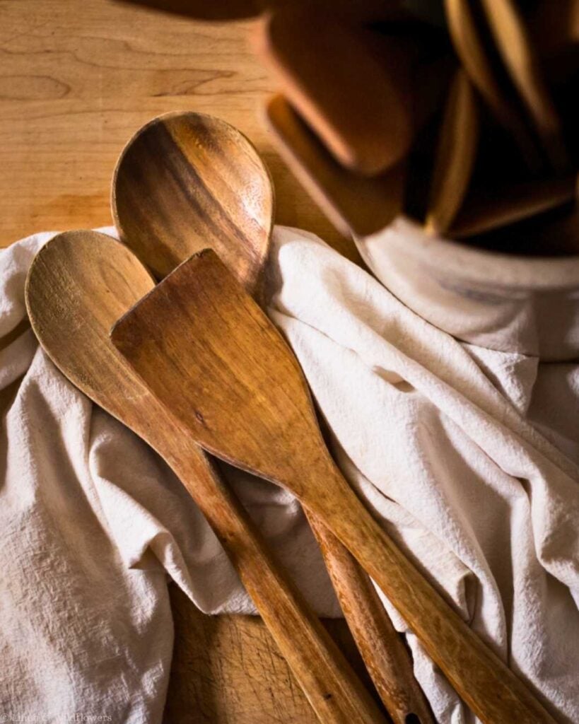 Wooden spoons and spatula on a linen towel, a common mistakes that ruin wooden utensils blog feature.