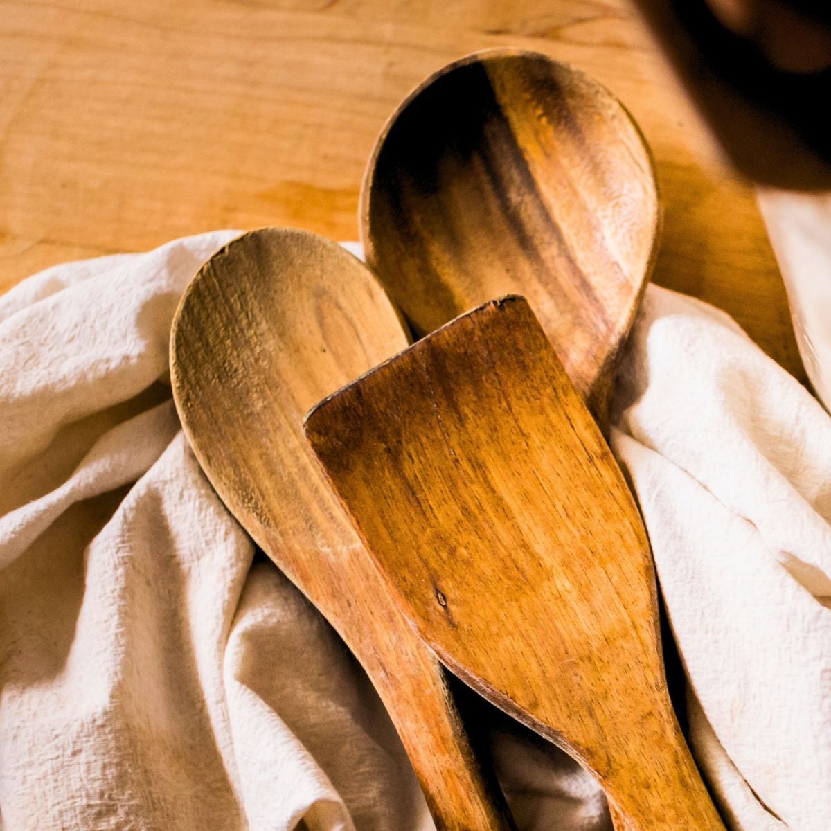 Wooden spoons and spatula resting on a linen cloth, illustrating common mistakes that ruin wooden utensils.