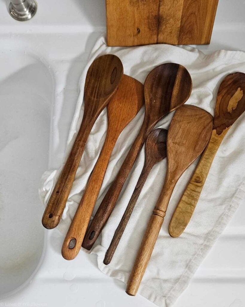 Wooden spoons laid out to air dry on a linen towel after washing, showing the correct way to dry wooden utensils.