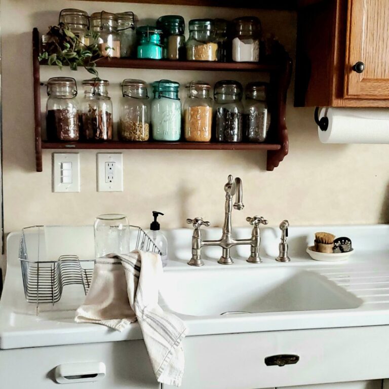 Budget-friendly farmhouse kitchen with vintage mason jar spice shelf, apron sink, and bridge faucet — cozy cottage kitchen decor ideas.